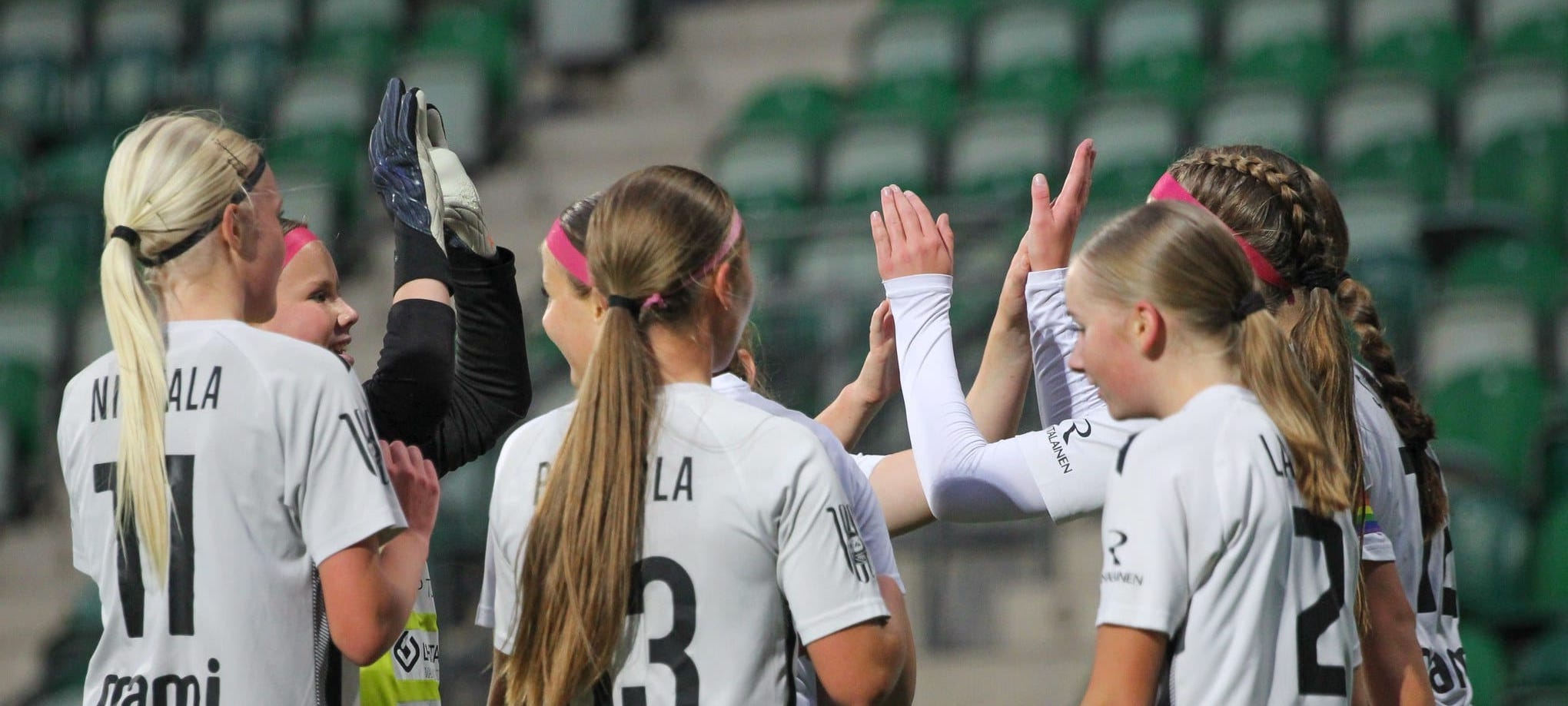 Kuusi yläkouluikäistä TPS:n jalkapalloilijatyttöä kannustavat toisiaan ylävitosilla.